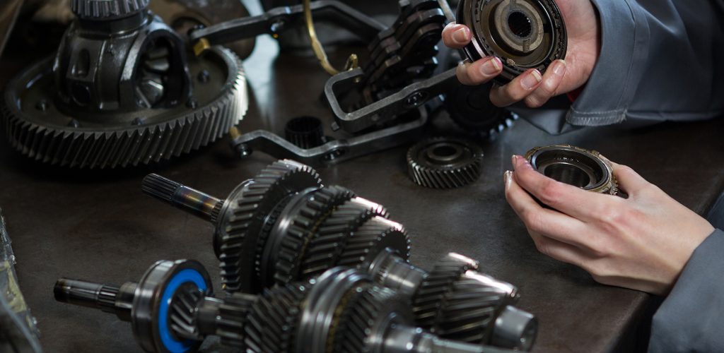 Close-up of female mechanic holding spare parts of car at repair garage